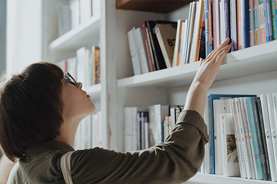 Frau stöbert in Bücherregal