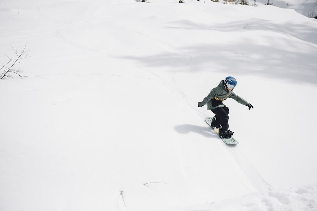 Kind fährt mit refurbed Snowboard auf der Piste